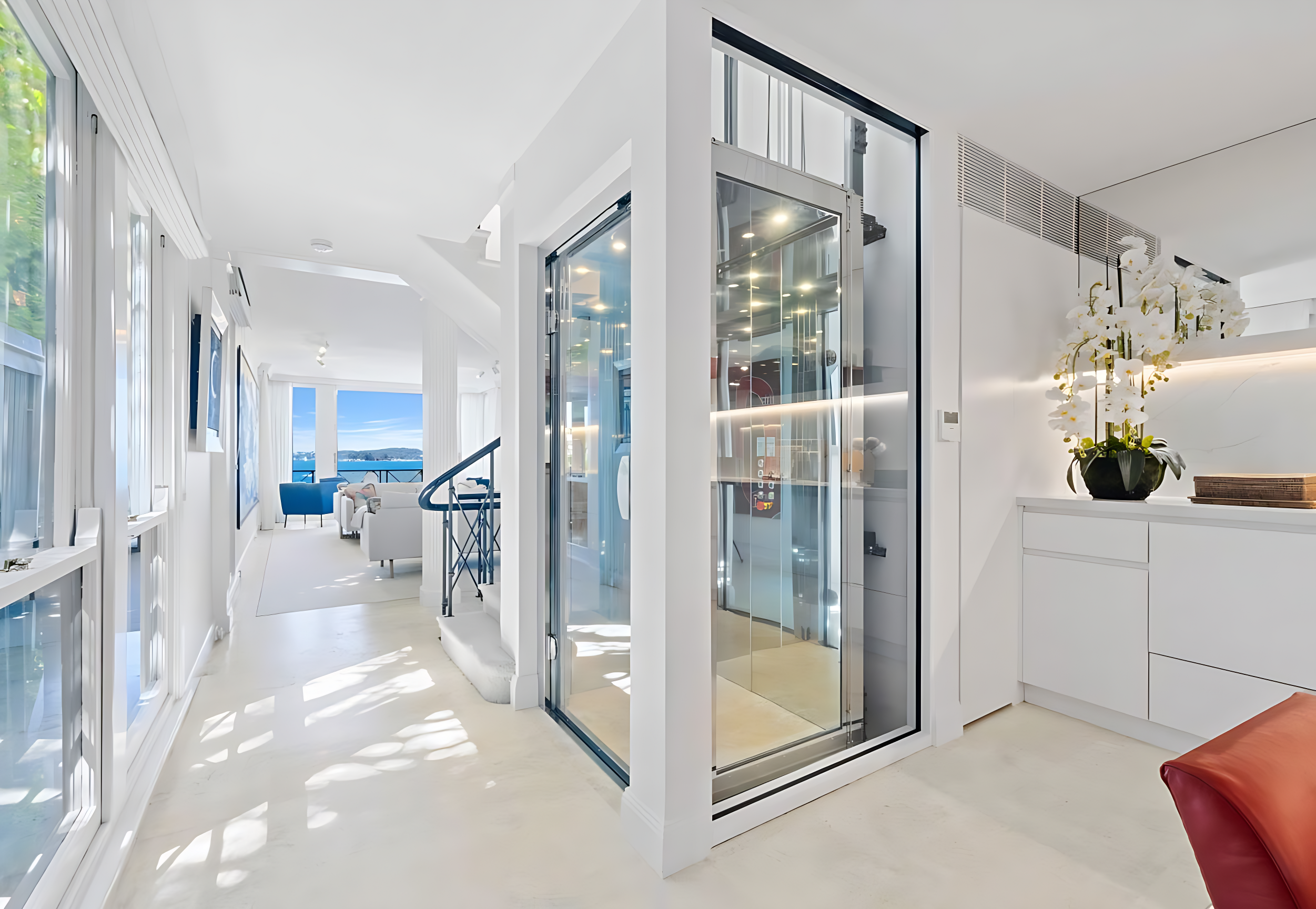 Elevator Boutique glass home elevator with a glass swing door in a bright white waterfront home