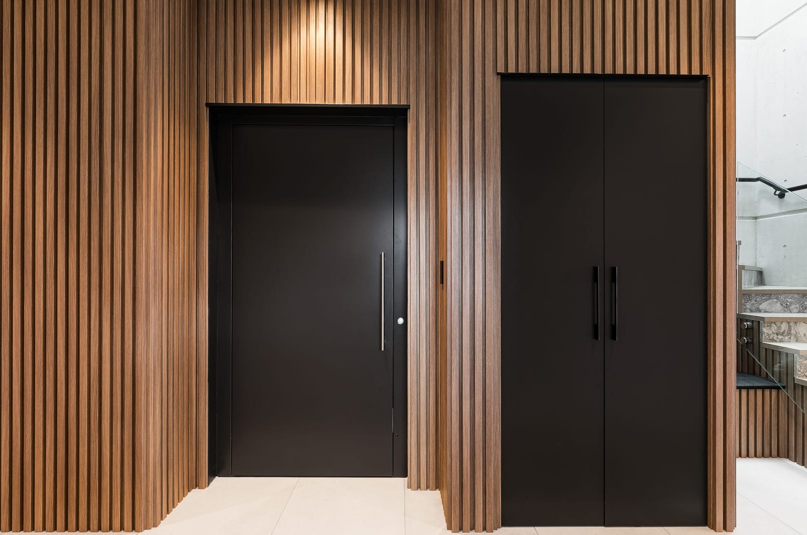 Elevator Boutique black aluminum swing door set into a timber batten wall