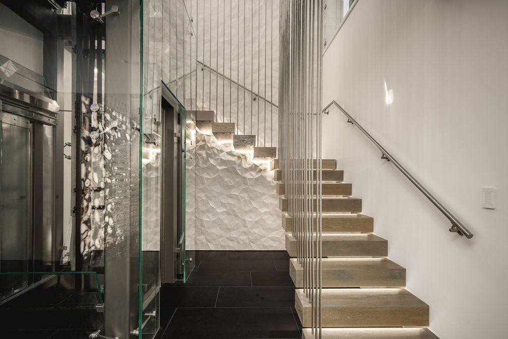 Glass-enclosed Elevator Boutique home elevator beside a floating oak staircase in Beverly Hills