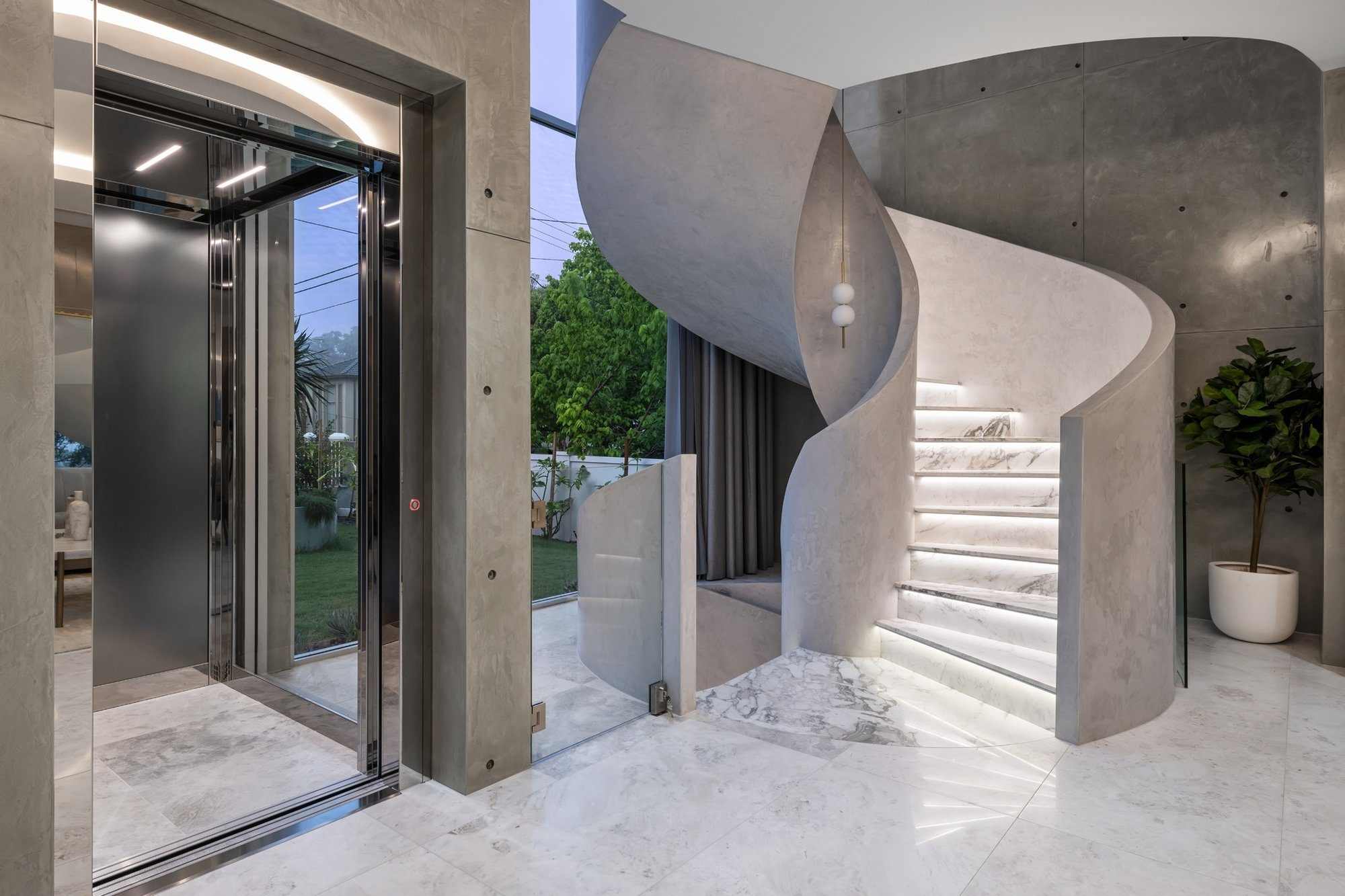 Strathfield Home Elevator E Series glass home elevator beside a sculptural spiral staircase in Strathfield